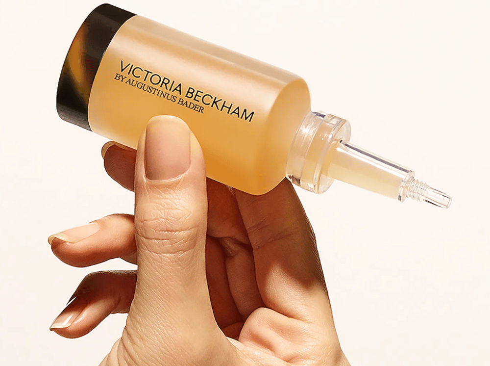 Woman's hand holding Victoria Beckham cosmetics bottle